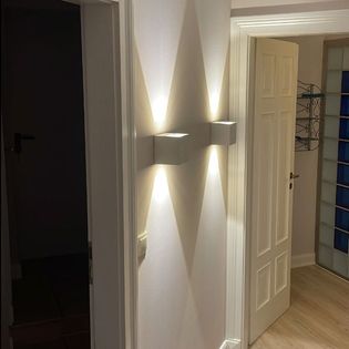 Ein Flur mit zwei Wandleuchten, die sanftes Licht auf die Wände werfen