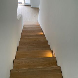 Eine Treppe mit Holzstufen, die von sanften Lichtern beleuchtet wird